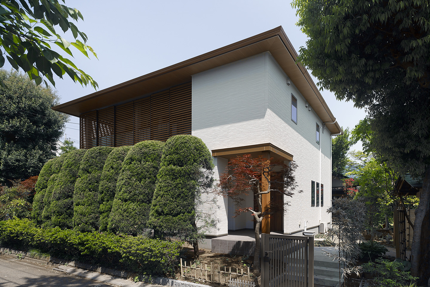 木のルーバーが緑と調和する家